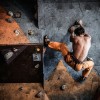 Muscular man practicing rock-climbing on a rock wall indoors