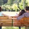Lonely woman sitting with couple in park on a sunny day